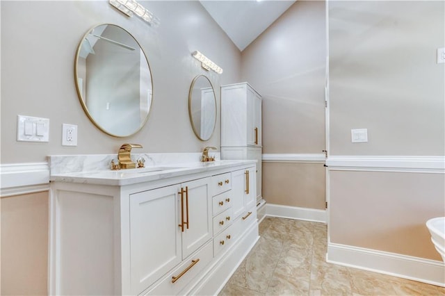 bathroom with vaulted ceiling, double vanity, a sink, and baseboards