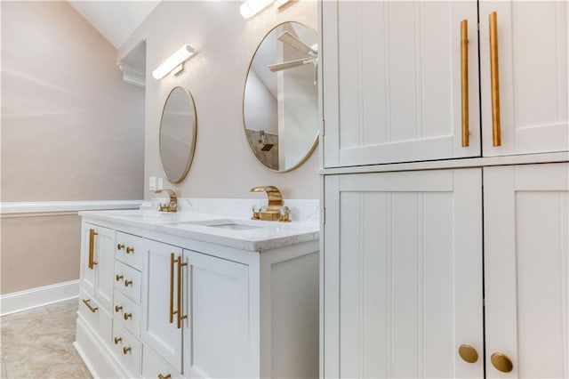 full bath featuring double vanity, a sink, and baseboards