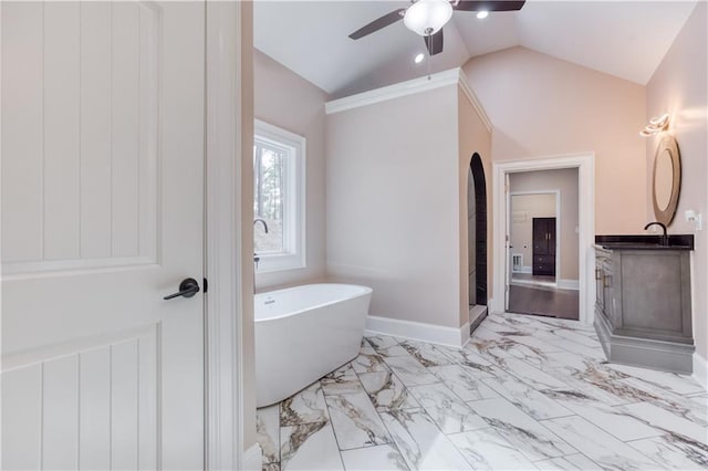 full bathroom with baseboards, lofted ceiling, marble finish floor, vanity, and a freestanding tub