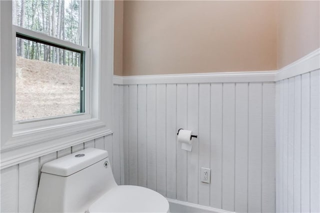 bathroom with wainscoting, plenty of natural light, and toilet