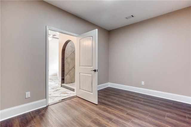 spare room with dark wood-style flooring, visible vents, and baseboards