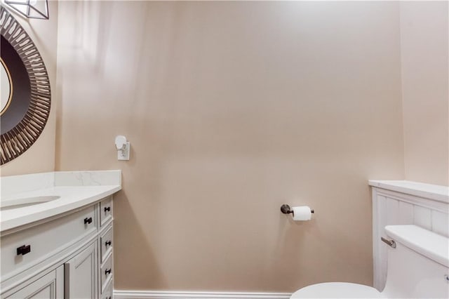 bathroom featuring toilet, vanity, and baseboards