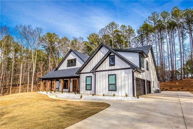 modern inspired farmhouse with roof with shingles, concrete driveway, an attached garage, board and batten siding, and a front yard