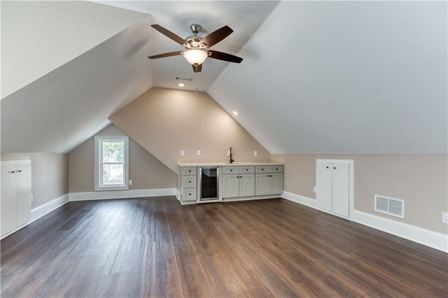 bonus room featuring dark wood-style flooring, visible vents, a sink, beverage cooler, and baseboards