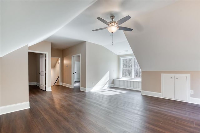 bonus room featuring lofted ceiling, dark wood-style flooring, a ceiling fan, and baseboards