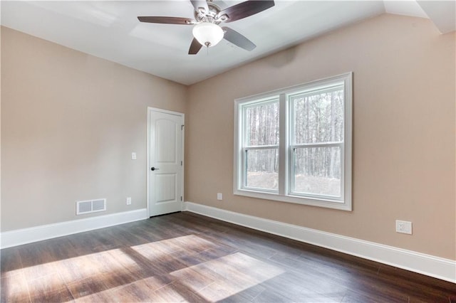 empty room with dark wood-style floors, visible vents, ceiling fan, and baseboards