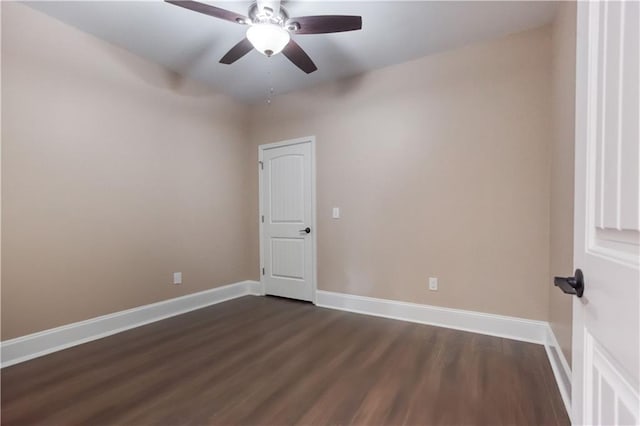 spare room featuring dark wood-style flooring, a ceiling fan, and baseboards