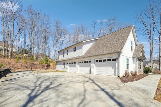 view of property exterior with an attached garage, driveway, and a shingled roof