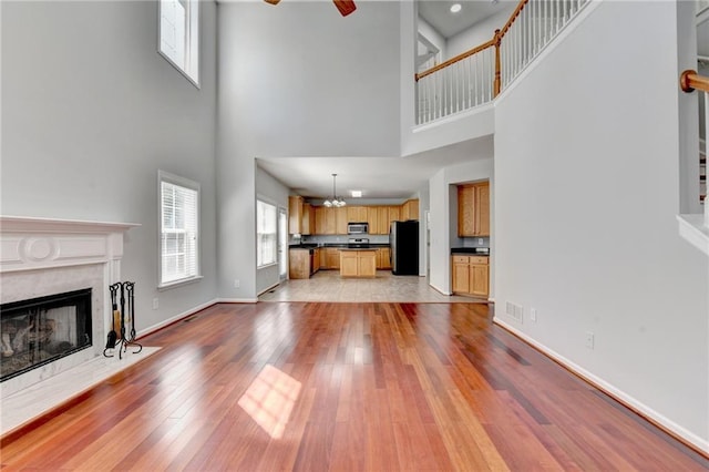 3805 Roxwood Park Dr, Buford, GA 30518 - unfurnished living room with a high ceiling, a fireplace, light wood-type flooring, a ceiling fan, and stairs