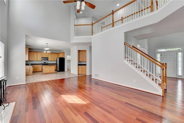 3805 Roxwood Park Dr, Buford, GA 30518 - unfurnished living room featuring a towering ceiling, stairs, ceiling fan, light wood-type flooring, and baseboards