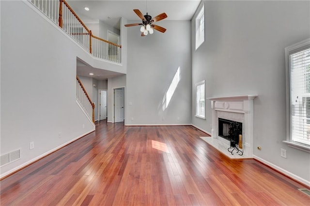 3805 Roxwood Park Dr, Buford, GA 30518 - unfurnished living room with a premium fireplace, a high ceiling, a ceiling fan, stairs, and wood finished floors