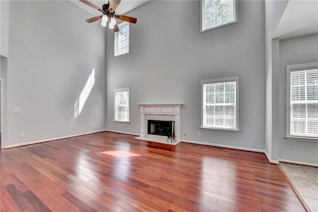 3805 Roxwood Park Dr, Buford, GA 30518 - unfurnished living room featuring a towering ceiling, a premium fireplace, hardwood / wood-style flooring, ceiling fan, and baseboards