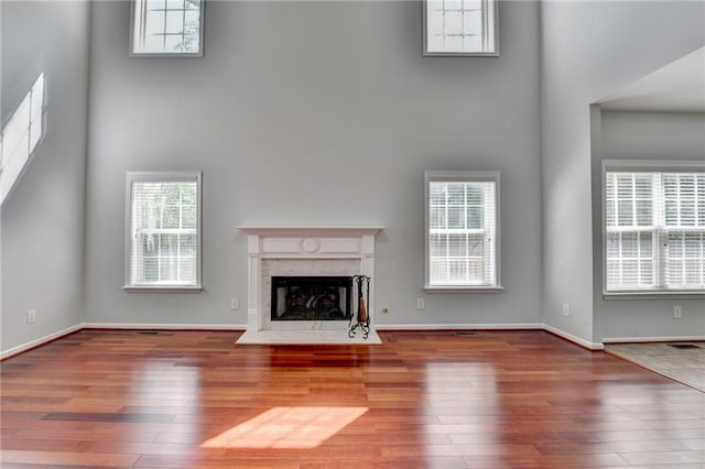 3805 Roxwood Park Dr, Buford, GA 30518 - unfurnished living room featuring a towering ceiling, hardwood / wood-style flooring, a high end fireplace, and baseboards