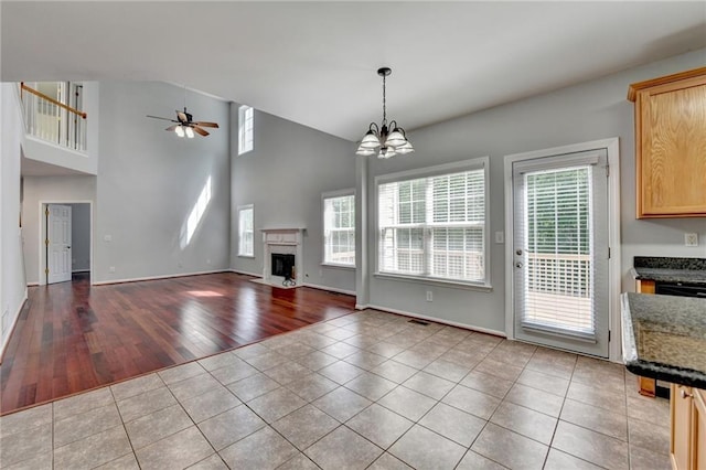 3805 Roxwood Park Dr, Buford, GA 30518 - unfurnished living room with tile patterned flooring, a ceiling fan, a chandelier, a high end fireplace, and high vaulted ceiling