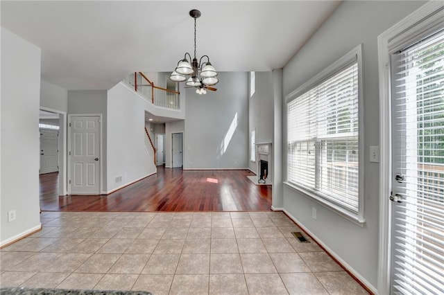 3805 Roxwood Park Dr, Buford, GA 30518 - unfurnished dining area with tile patterned flooring, a chandelier, baseboards, a fireplace, and stairs