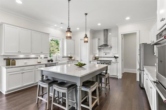 kitchen featuring a center island, light stone countertops, wall chimney exhaust hood, white cabinetry, and backsplash