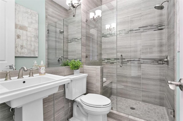 bathroom featuring toilet, a shower with shower door, and sink