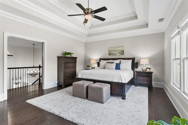 bedroom with crown molding, ceiling fan, dark hardwood / wood-style flooring, multiple windows, and a tray ceiling