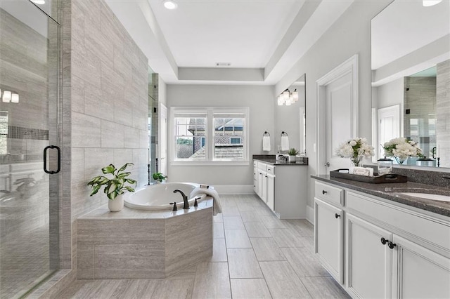 bathroom featuring a tray ceiling, vanity, and shower with separate bathtub