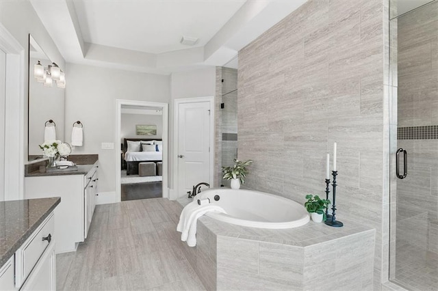 bathroom featuring vanity, a raised ceiling, and separate shower and tub