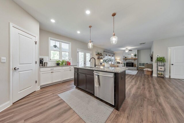 kitchen with stainless steel dishwasher, wood-type flooring, sink, and hanging light fixtures