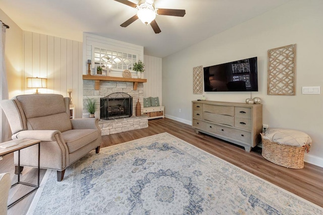 living room featuring dark wood-type flooring, ceiling fan, and a fireplace