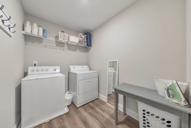 clothes washing area featuring washer and clothes dryer and light hardwood / wood-style flooring