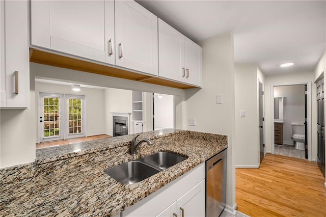 3655 Habersham Rd NE Unit 203, Atlanta, GA 30305 - kitchen with stainless steel dishwasher, a sink, a glass covered fireplace, stone countertops, and white cabinets