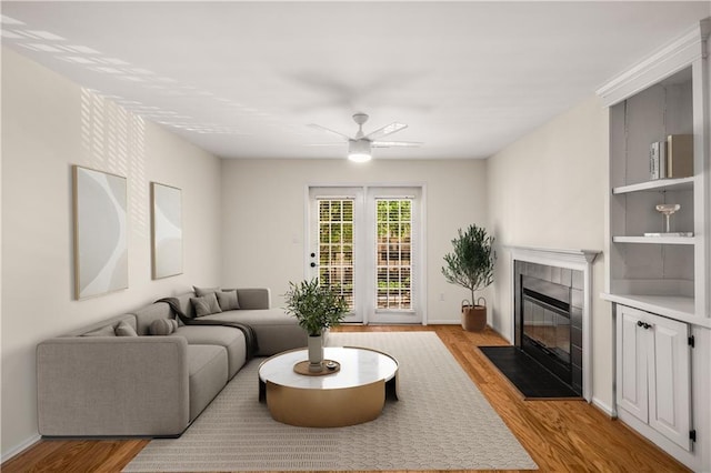 3655 Habersham Rd NE Unit 203, Atlanta, GA 30305 - living area featuring a tiled fireplace, light wood-style floors, a ceiling fan, and baseboards