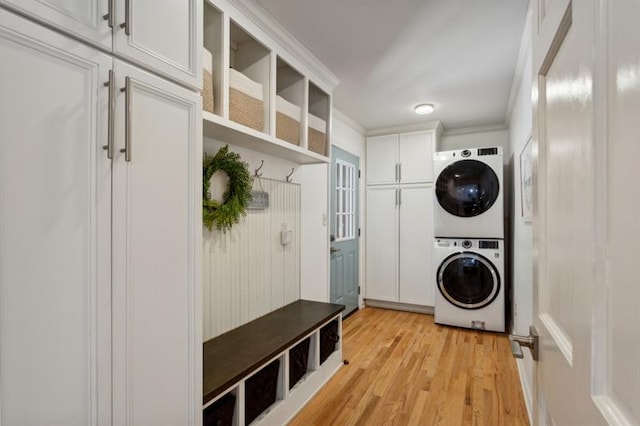 mudroom with stacked washer and dryer, crown molding, and light hardwood / wood-style floors