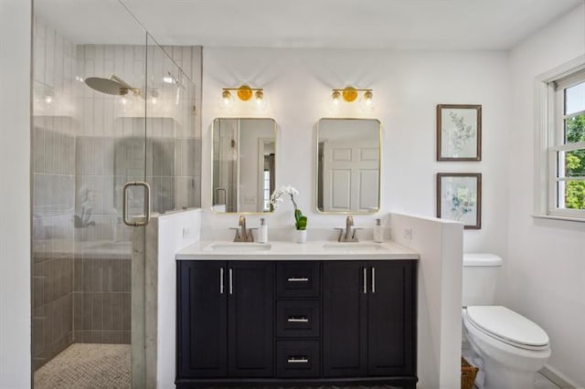 bathroom featuring a shower with door, vanity, and toilet