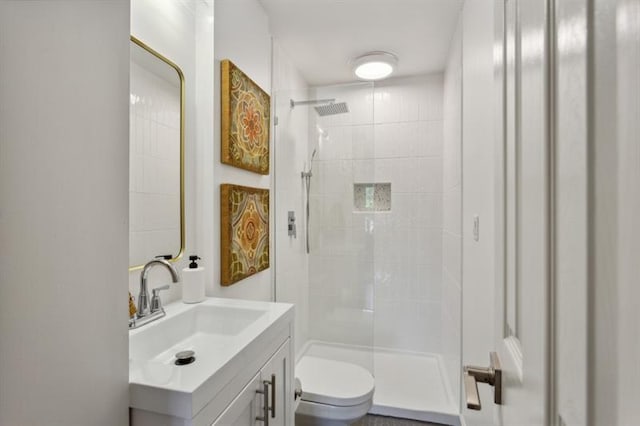 bathroom with tiled shower, vanity, and toilet