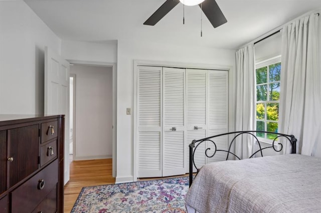 bedroom featuring multiple windows, light hardwood / wood-style flooring, a closet, and ceiling fan