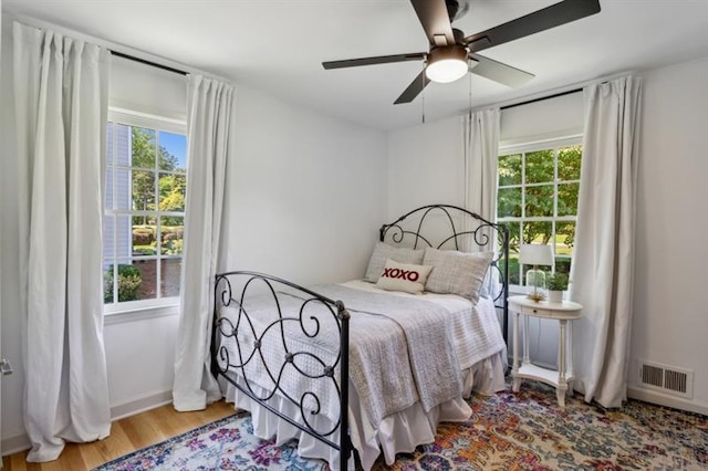 bedroom featuring multiple windows, wood-type flooring, and ceiling fan