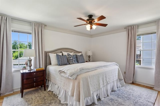 bedroom with ceiling fan, ornamental molding, and light hardwood / wood-style floors