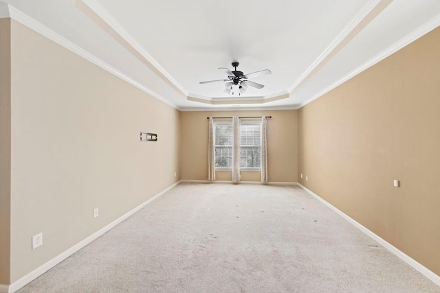 spare room featuring a tray ceiling, ceiling fan, light carpet, and ornamental molding