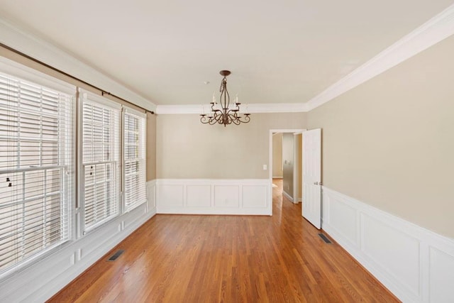 unfurnished dining area featuring a chandelier, wood-type flooring, and ornamental molding