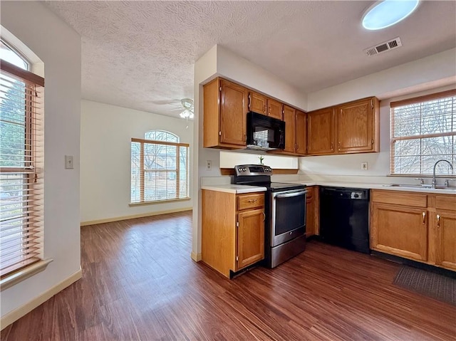 kitchen featuring sink, dark wood-type flooring, black appliances, and a textured ceiling