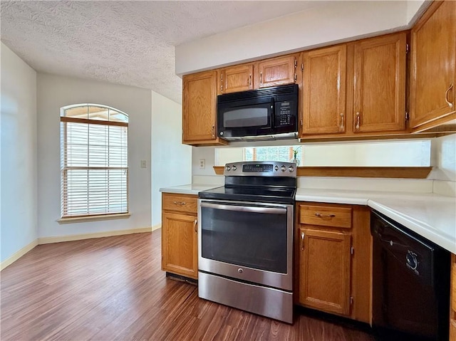 kitchen featuring dark wood-type flooring, a textured ceiling, and black appliances