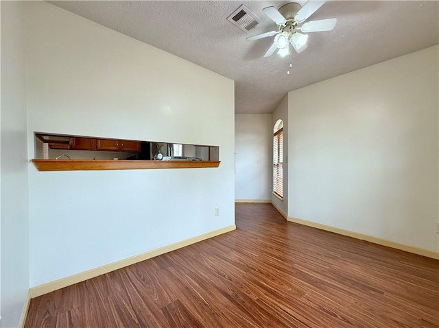 unfurnished room featuring a textured ceiling, dark hardwood / wood-style floors, and ceiling fan