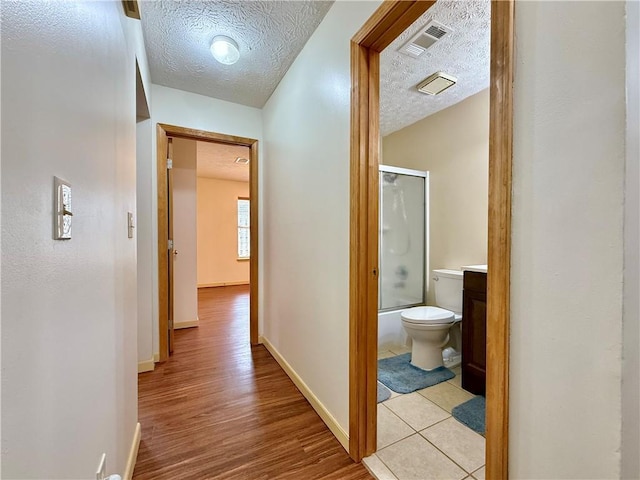 hallway featuring a textured ceiling and light hardwood / wood-style floors