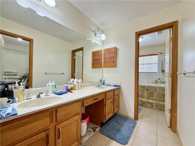 bathroom with vanity, tiled bath, tile patterned flooring, and a textured ceiling