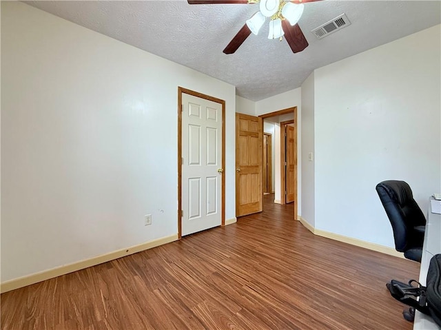 unfurnished office with ceiling fan, hardwood / wood-style floors, and a textured ceiling