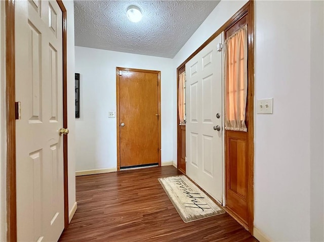 doorway with dark wood-type flooring and a textured ceiling