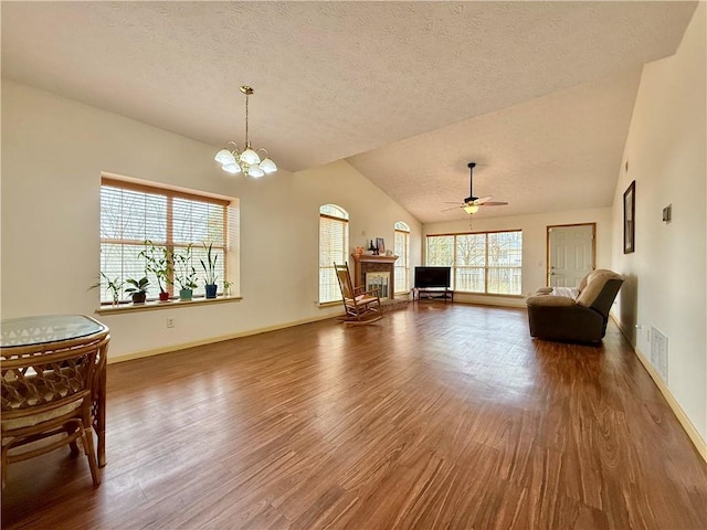 sitting room featuring hardwood / wood-style flooring, vaulted ceiling, ceiling fan with notable chandelier, and a textured ceiling