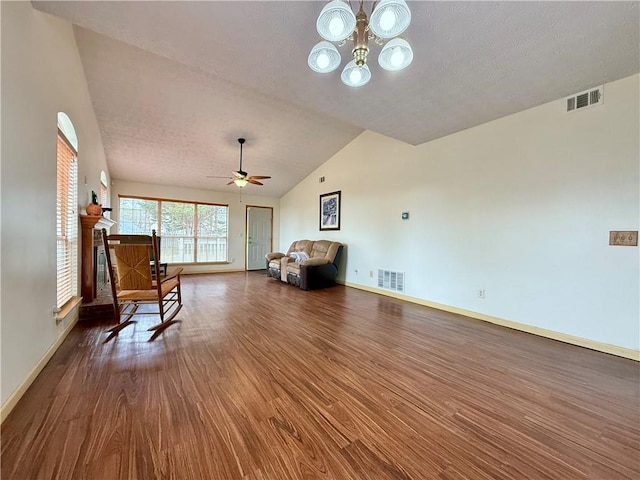 living area featuring lofted ceiling, hardwood / wood-style floors, ceiling fan with notable chandelier, and a textured ceiling