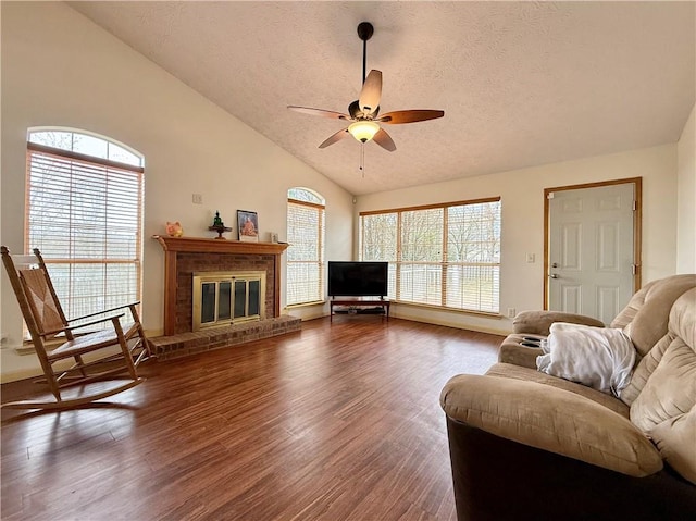 living room featuring high vaulted ceiling, a brick fireplace, a textured ceiling, dark hardwood / wood-style flooring, and ceiling fan