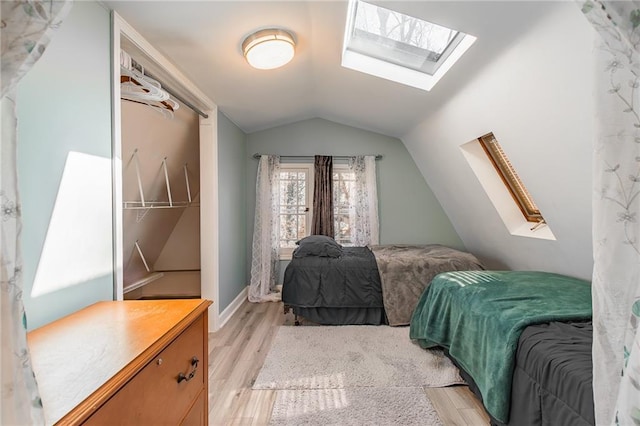 bedroom with light hardwood / wood-style floors and vaulted ceiling with skylight