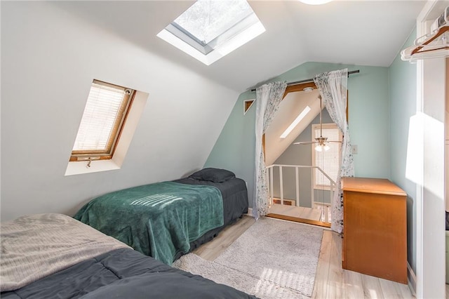 bedroom featuring light hardwood / wood-style floors and vaulted ceiling with skylight