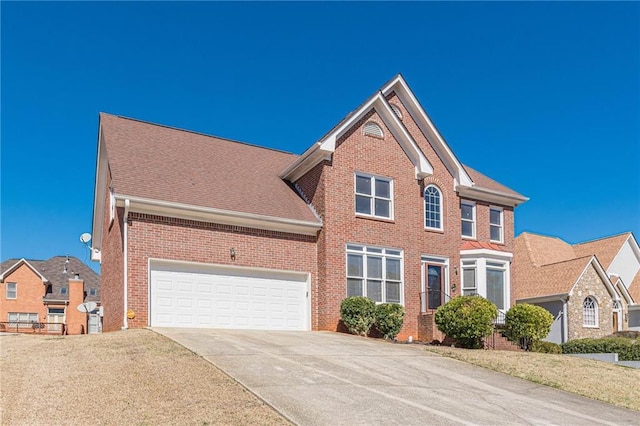 colonial house with a garage, driveway, brick siding, and a shingled roof